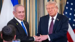 Benjamin Netanyahu et Donald Trump se serrent la main tout en posant pour les médias.