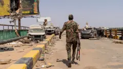 جندي من القوات المسلحة السودانية يسير على جسر شمبات الذي كان يربط أم درمان بحي بحري في الخرطوم على الضفة المقابلة لنهر النيل (صورة أرشيفية)