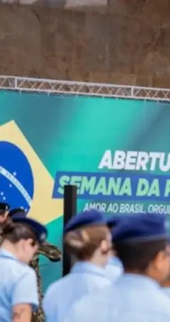 Militares em fileira em frente a um banner com a bandeira do Brasil