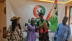 Two men holding flag wit one woman by di side