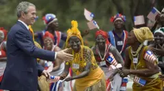 Former US President George W. Bush and dancers wey wear traditional attire. 
