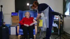 A nurse vaccinating an elderly patient
