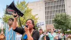 Demonstrators hold signs while protesting against redistricting efforts