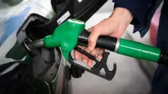 A person fills up their car with a petrol pump. 