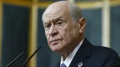 Devlet Bahçeli kürsüde konuşma yapıyor ve lacivert bir kravat takıyor