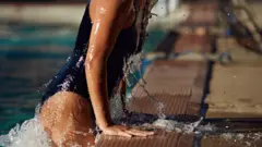 Mujer en traje de baño saliendo de una piscina