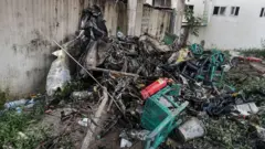 Algunos de los escombros del avión mezclados con sillas de madera de la escuela chamuscadas y un extintor tirados en el suelo