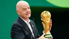 O presidente da Fifa, Gianni Infantino, segura o troféu da Copa do Mundo enquanto discursa