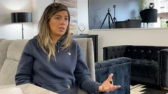 Priscila Sousa usa um agasalho azul e faz gesto com a mão esquerda durante entrevista