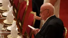 مرداک در یک ضیافت، کاغذی در دست دارد و به آن نگاه میکند