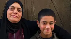 Falestin Nakhle with her arm around Karim, sitting on a doorstep