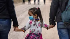 An immigrant child glances back towards Mexico after crossing the border into the United States on April 14, 2021 in La Joya, Texas