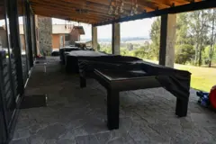 Una vista del exterior de la cabaña, con muebles y un patio con vista al bosque.