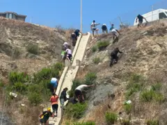 Migrantes escalam uma área elevada com cercas que separa Marrocos de Ceuta.