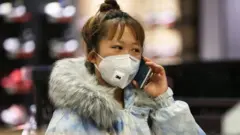 A woman wearing a protective mask uses a smartphone as she shops at a shopping mall in Shenyang in China's northeastern Liaoning province