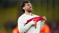 Orkun Kökçü Türkiye formasıyla attığı gol sonrası formadaki Türk bayrağını göstererek seviniyor.