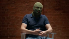 Мужчина в балаклаве сидит на стуле.