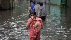 পানিবন্দী রাস্তায় এক নারী ও নৌকায় কিছু বাসিন্দা