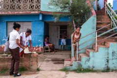 Mulheres conversando na porta de uma casa. Há uma criança do lado