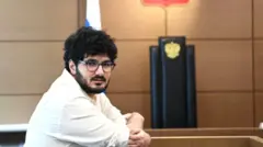 Армен Арамян, мужчина с черными волосами и бородой в белой рубашке в зале суда в 2022 году