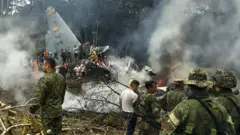 This screen grab shows soldiers and rescuers near an Air Force Hercules emitting thick smoke after the aircraft crashed during takeoff in Puerto Leguizamo, Colombia, near the southern border with Ecuador, on March 23, 2026. 