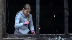 Девушка в обгоревшем оконном проеме после удара российского дрона в Днепропетровской области