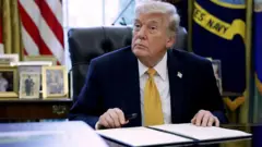 ඇමෙරිකානු ජනාධිපති ඩොනල්ඩ් ට්‍රම්ප් ධවල මන්දිරයේ සිය කාර්යාලයේ සිටින අවස්ථාවක් 