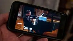Игорь Левит на экране мобильного телефона.