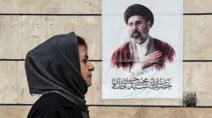 Bir başörtülü kadın, İran lideri Hamaney'in fotoğrafının önünden geçiyor