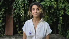 Insaf Dimassi, uma mulher jovem, de cabelos cacheados, olhando para a câmera