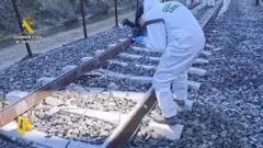 Un agente de la Guardia Civil toma fotos de los raíles por los que pasaron los trenes sinistrados.