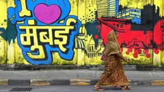 Une femme passe devant une fresque murale sur laquelle on peut lire « J’aime Mumbai » le long d’une rue de Mumbai, le 31 août 2023. (Photo d’Indranil MUKHERJEE / AFP) (Photo de INDRANIL MUKHERJEE/AFP via Getty Images)