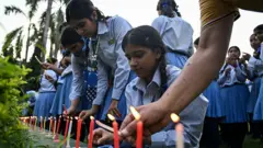 Estudantes e outras pessoas acendem velas em homenagem ao alpinista Nirmal Purja e a seus companheiros, mortos em uma avalanche no Paquistão