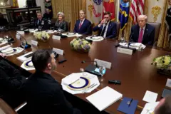 Zelensky, Trump e várias outras autoridades, sentados em torno de uma mesa de madeira na Casa Branca