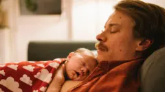 Bebê dormindo no peito do pai
