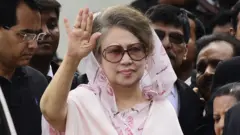 خالده ضیا با شال صورتی کمرنگ و عینک آفتابی، در ماه اپریل ۲۰۱۵ دست تکان میدهد.