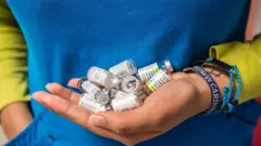 A nurse carries empty vials of HPV vaccine