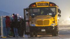 Unos migrantes hacen fila para subir a un autobús escolar que los llevará de Floyd Bennett Field a un instituto local donde protegerse de la tormenta en enero de 2024, en Brooklyn, Nueva York, Estados Unidos.imated wind speeds to be more than 70 mph. on January 09, 2024 in the Brooklyn borough of New York City.