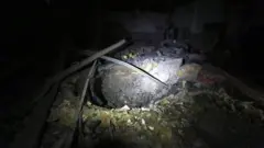 వైమానిక దాడి జరిగిన ప్రదేశంలో బాంబు ధాటికి ఏర్పడ్డ గొయ్యి