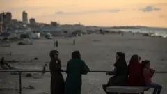 يقضي الفلسطينيون النازحون وقتهم على الشاطئ مقابل خيامهم الممتدة على طول ميناء غزة، في غزة، في 13 نوفمبر/تشرين الثاني 2025. 