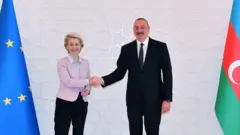 Фон дер Ляйен пожимает руку Ильхаму Алиеву на фоне флагов ЕС и Азербайджана.