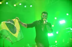 O cantor Gusttavo Lima segura uma bandeira do Brasil no palco