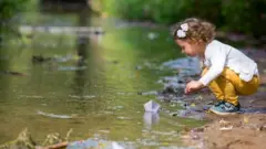Uma criança brincando em um lago