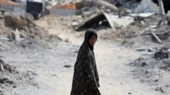 سيدة فلسطينية في غزة تبدو شاحبة تقف وسط طريق فارغ ومن حولها ركام