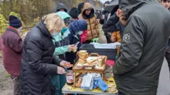 Des bénévoles distribuent des sandwichs pour le petit-déjeuner dans un camp de migrants à l'ouest de Dunkerque.