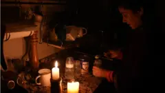 Mulher acende velas para ter luz durante o apagão na Argentina