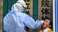 A medical worker takes a swab sample from a woman to be tested for the COVID-19 novel coronavirus in Wuhan, in Chinas central Hubei province on May 13, 2020.