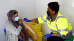 አንዲት ሴት ክትባቱን ስትወስድ