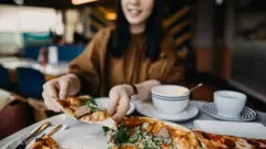 Mulher pegando um pedaço de pizza