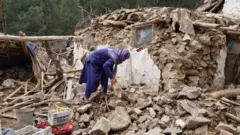 Khost, Afghanistan. Woman surrounded by rubbles.